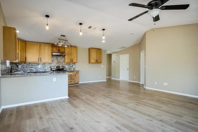 kitchen with light wood-type flooring, vaulted ceiling, hanging light fixtures, and stainless steel gas range