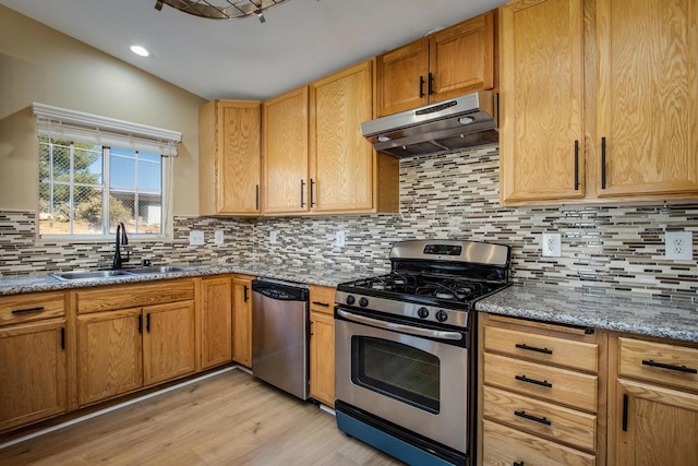 kitchen featuring decorative backsplash, appliances with stainless steel finishes, light hardwood / wood-style flooring, and sink