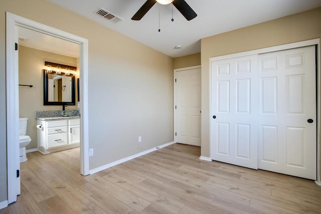 unfurnished bedroom featuring ensuite bathroom, ceiling fan, a closet, and light hardwood / wood-style flooring