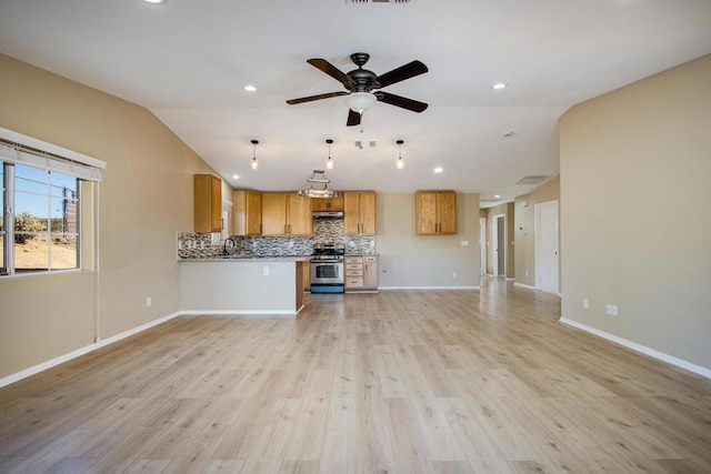 kitchen featuring kitchen peninsula, stainless steel stove, light hardwood / wood-style flooring, and lofted ceiling