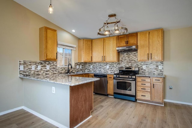 kitchen with light stone countertops, backsplash, kitchen peninsula, light hardwood / wood-style floors, and appliances with stainless steel finishes