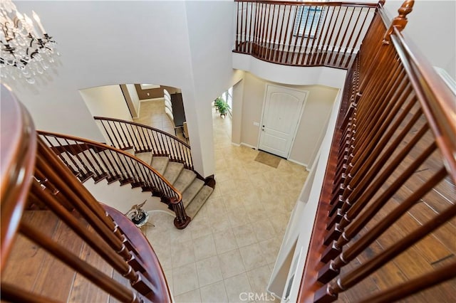 stairway with tile patterned flooring and a high ceiling