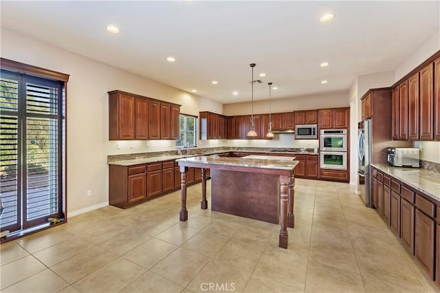 kitchen featuring a breakfast bar area, appliances with stainless steel finishes, light stone countertops, a kitchen island, and decorative light fixtures