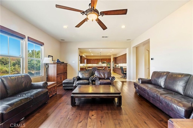 living room featuring ceiling fan and dark hardwood / wood-style flooring