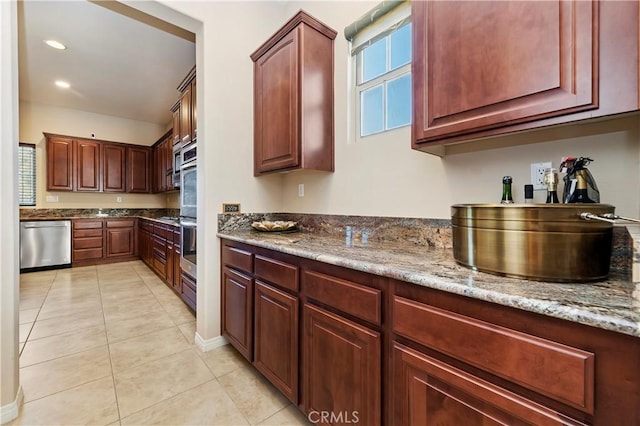 kitchen with stainless steel dishwasher, light stone counters, and light tile patterned floors