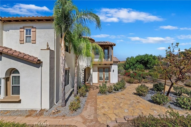 view of side of home with a balcony, a patio area, and french doors