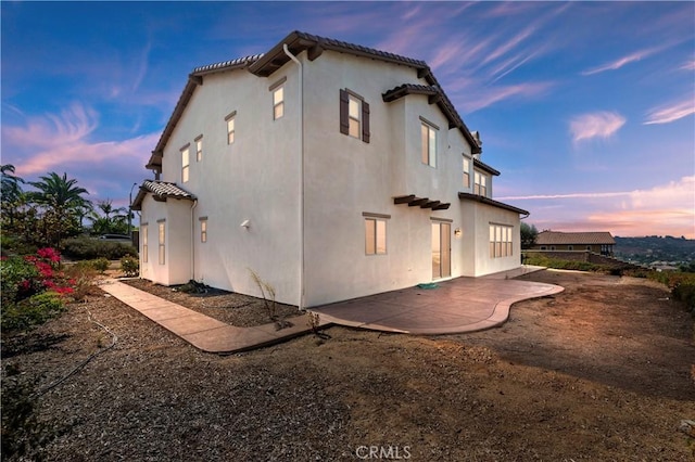 property exterior at dusk featuring a patio