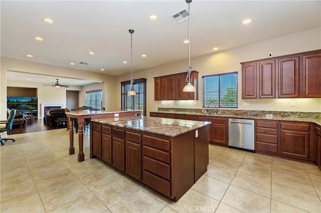 kitchen with pendant lighting, sink, dishwasher, a center island, and light stone counters