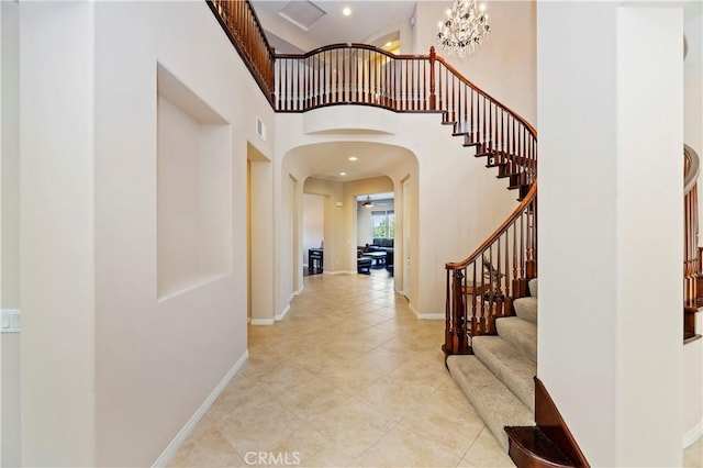 entryway featuring a chandelier, light tile patterned floors, and a high ceiling