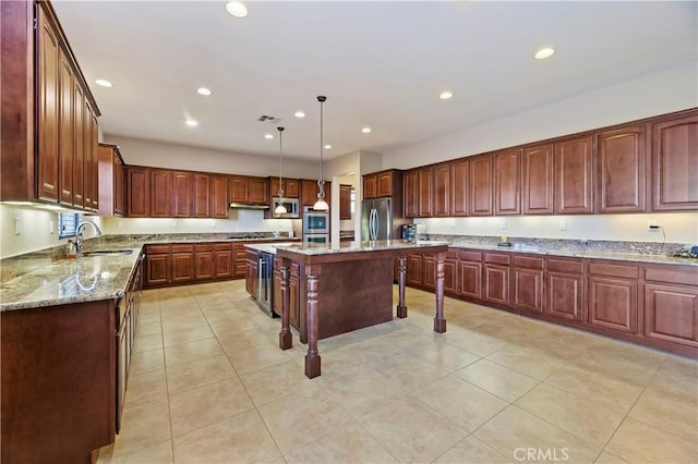 kitchen featuring sink, decorative light fixtures, a center island, appliances with stainless steel finishes, and light stone countertops