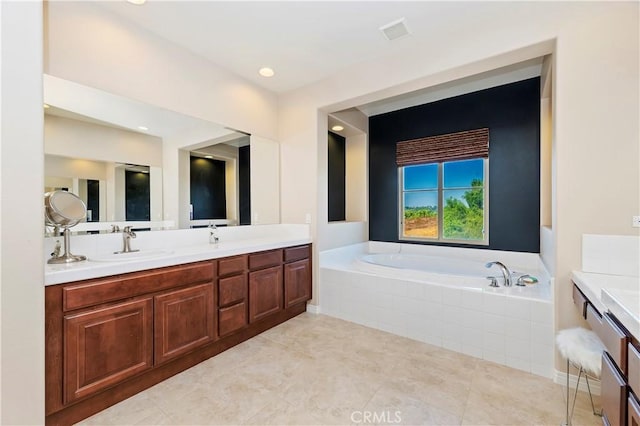 bathroom with a relaxing tiled tub, vanity, and tile patterned flooring