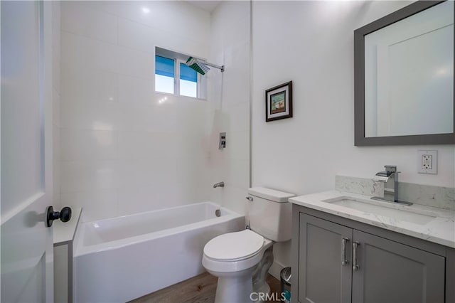 full bathroom with tiled shower / bath, vanity, hardwood / wood-style floors, and toilet