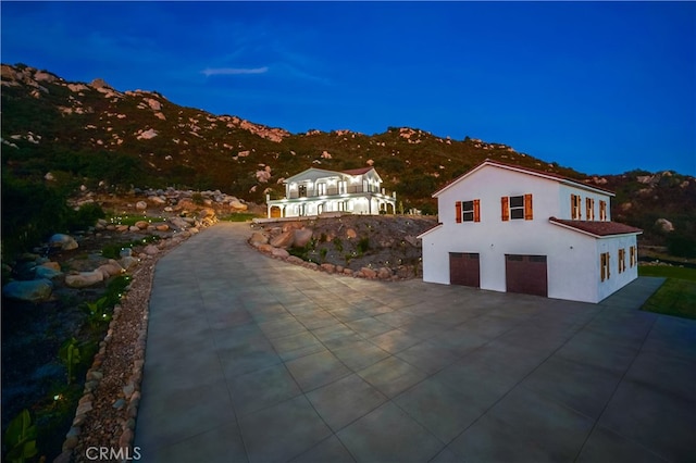 property exterior at dusk featuring a garage and a mountain view