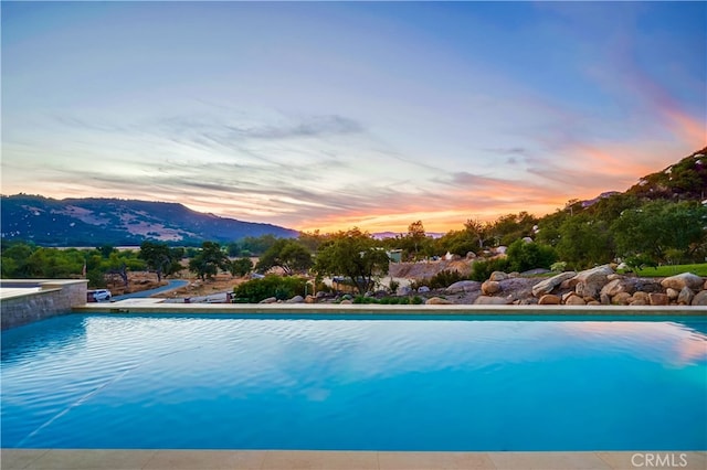 pool at dusk featuring a mountain view