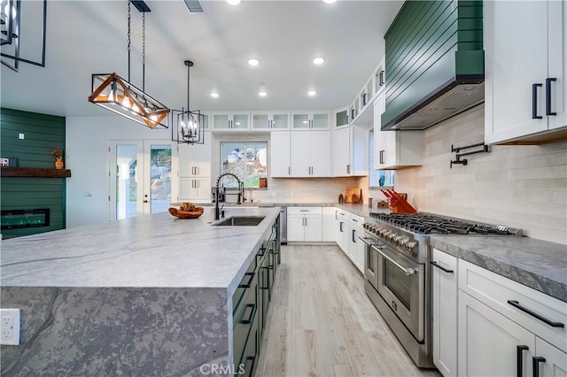 kitchen featuring a large island, white cabinetry, decorative light fixtures, premium range hood, and double oven range