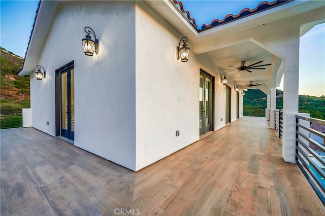 view of patio with ceiling fan and a balcony