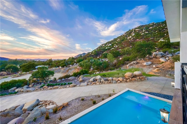 pool at dusk with a patio area