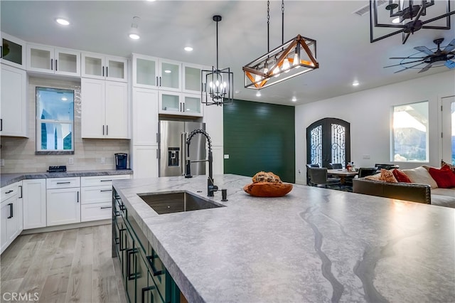 kitchen with sink, hanging light fixtures, white cabinetry, decorative backsplash, and stainless steel fridge with ice dispenser