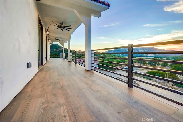 balcony at dusk featuring ceiling fan