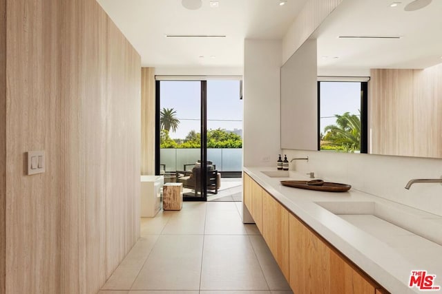 bathroom with tile patterned floors, a bathtub, vanity, and wood walls