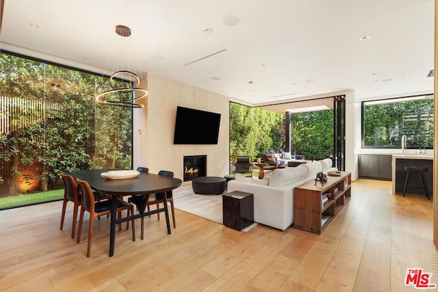 living room featuring sink, a fireplace, light hardwood / wood-style floors, and a chandelier