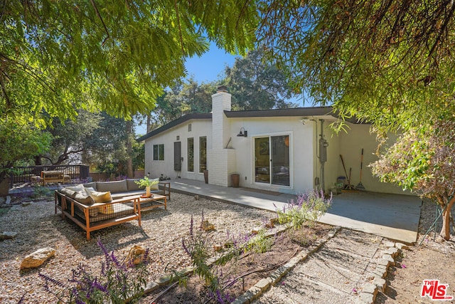 back of house with an outdoor living space and a patio area