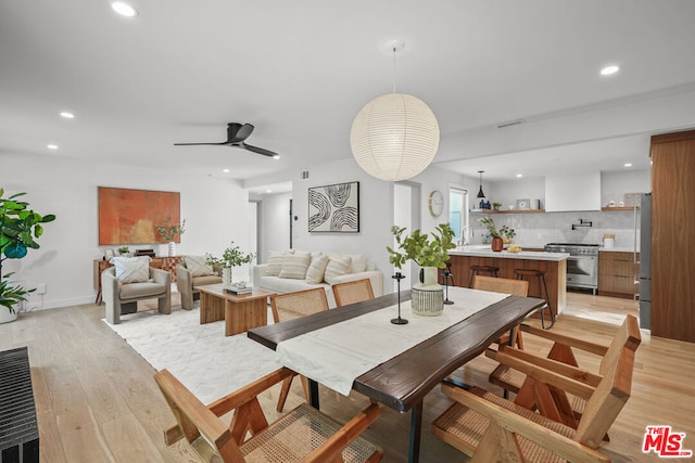 dining area featuring light hardwood / wood-style flooring, ceiling fan, and sink