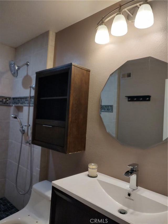 bathroom featuring vanity, toilet, and a tile shower