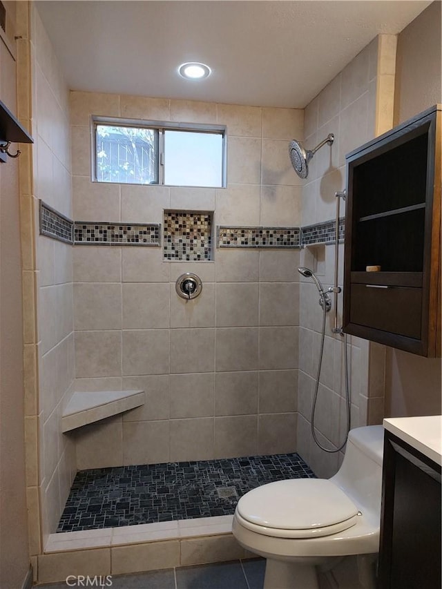 bathroom featuring tile patterned flooring, vanity, toilet, and a tile shower