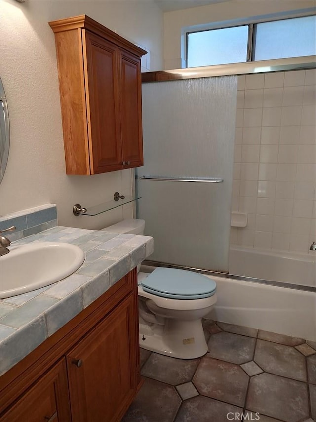 full bathroom with tile patterned floors, vanity, toilet, and bath / shower combo with glass door