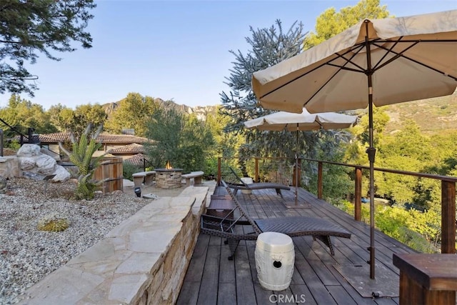 wooden deck featuring a mountain view and a fire pit