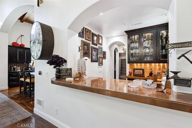 bar with decorative backsplash and dark wood-type flooring