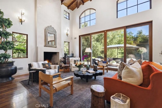 living room featuring hardwood / wood-style flooring, beam ceiling, a fireplace, and a wealth of natural light