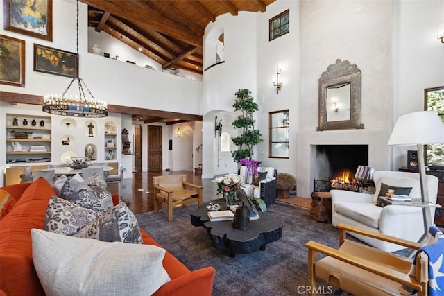 living room with high vaulted ceiling, beamed ceiling, wood-type flooring, wood ceiling, and a chandelier