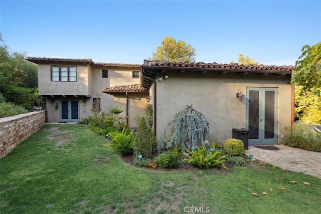 back of house with french doors and a lawn