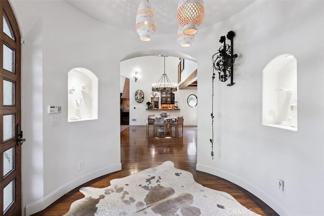 entrance foyer with a high ceiling, dark hardwood / wood-style flooring, and an inviting chandelier