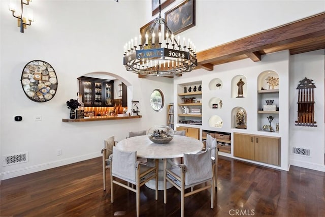 dining space featuring built in shelves, beamed ceiling, and dark hardwood / wood-style floors