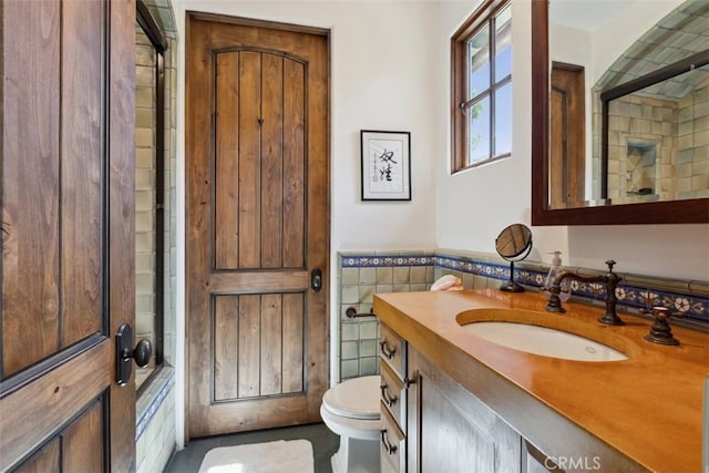 bathroom with vanity, tile walls, and toilet