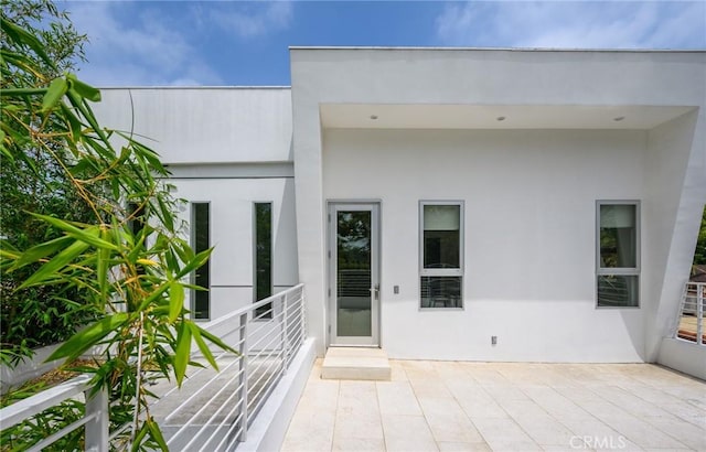 view of exterior entry featuring a patio area and stucco siding