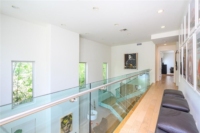 corridor with hardwood / wood-style flooring, visible vents, an upstairs landing, and recessed lighting