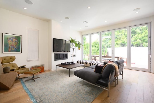 living room with light wood finished floors, visible vents, and recessed lighting