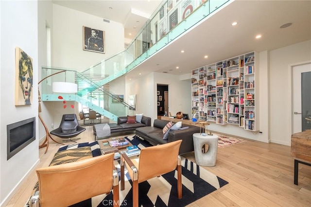 living area featuring baseboards, hardwood / wood-style floors, stairs, a high ceiling, and recessed lighting