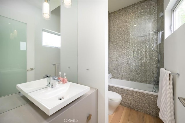 full bathroom with vanity, tiled shower / bath, toilet, and wood finished floors