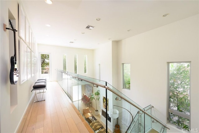 hall featuring light wood-type flooring, an upstairs landing, visible vents, and recessed lighting