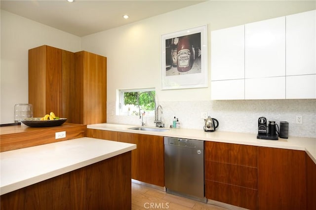 kitchen featuring a sink, light countertops, stainless steel dishwasher, brown cabinetry, and modern cabinets