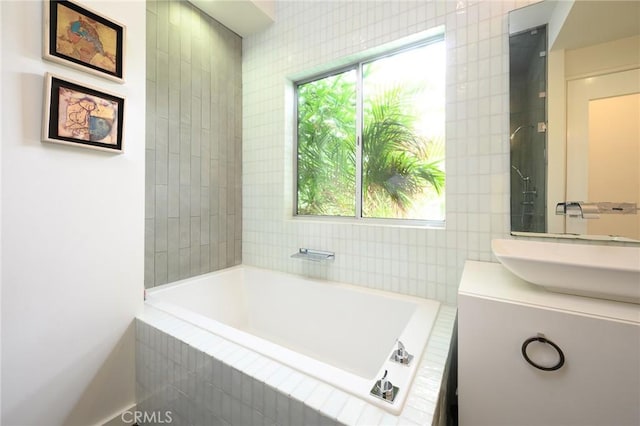 full bathroom with a relaxing tiled tub and vanity