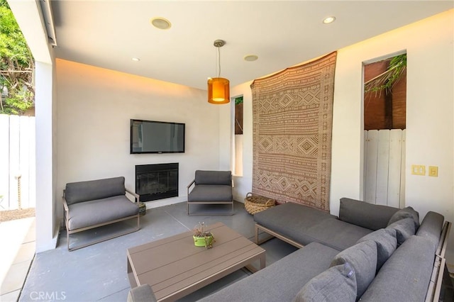 living room with concrete flooring, a glass covered fireplace, and recessed lighting