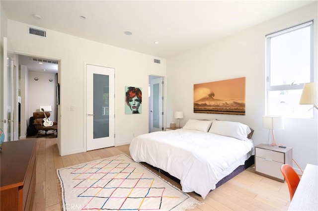 bedroom with light wood-style flooring, visible vents, and baseboards