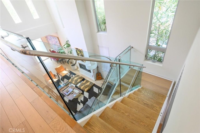 stairway with a healthy amount of sunlight and wood finished floors