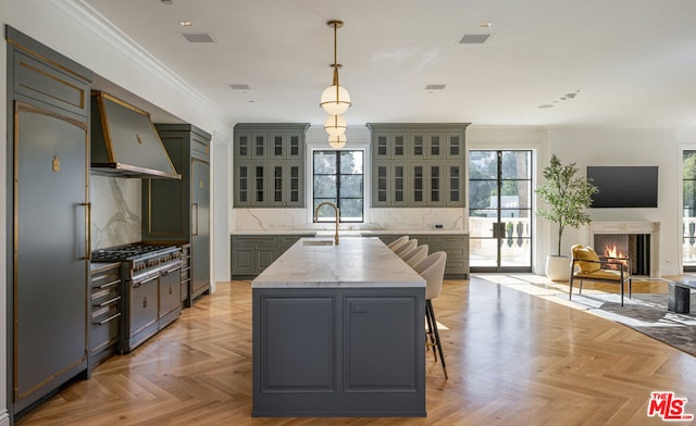 kitchen featuring hanging light fixtures, light parquet floors, high quality appliances, and a center island with sink